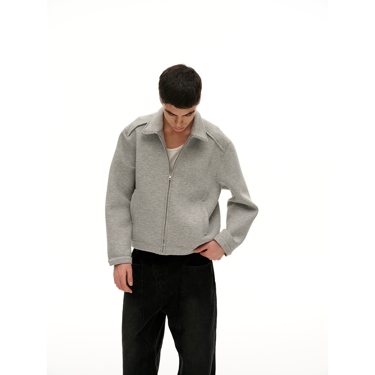 Closer view of a model wearing a light gray collared zip jacket with vertical pockets and black pants.