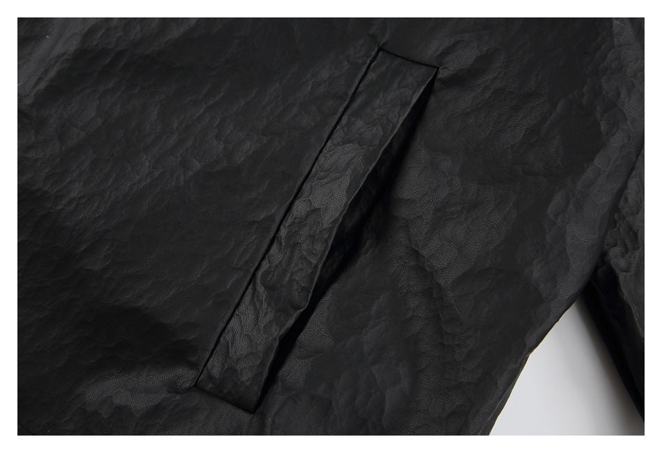 Close-up of a slanted welt pocket on the textured black jacket.