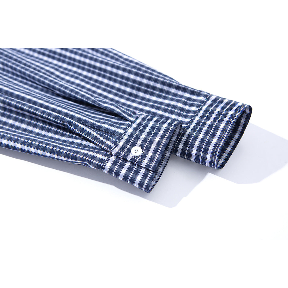 Close-up of the buttoned cuff and sleeve of a navy and white checked shirt.