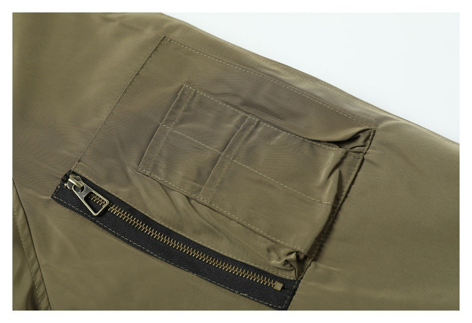 Close-up of an olive jacket pocket with stitched divisions and a brass-toned zipper.