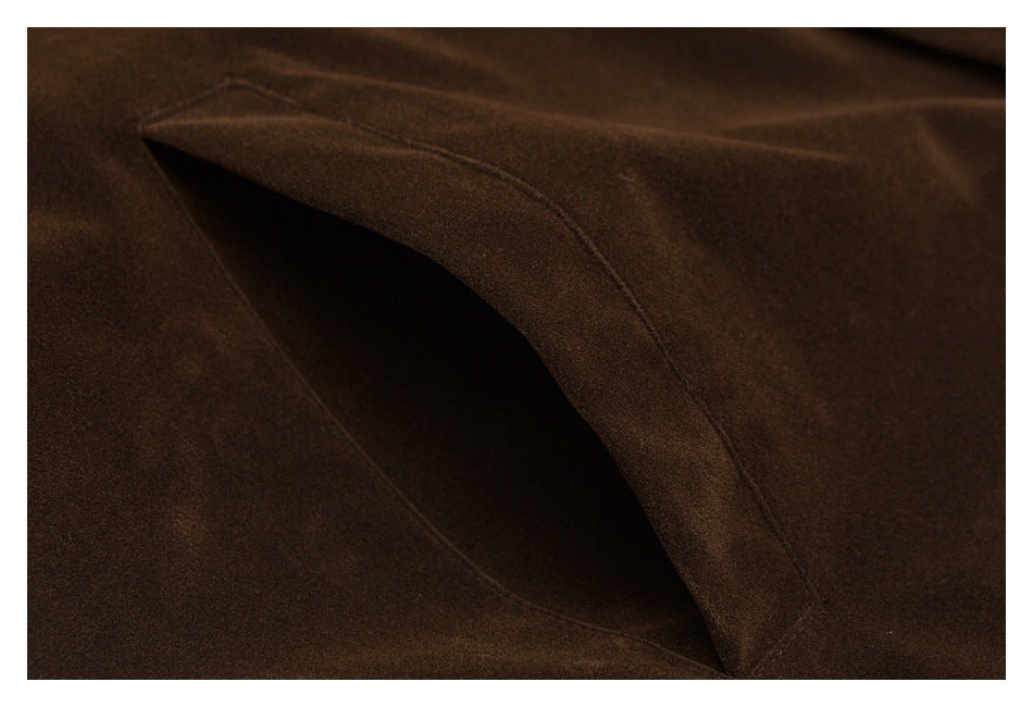 Close-up of a curved pocket opening stitched into dark brown fabric.