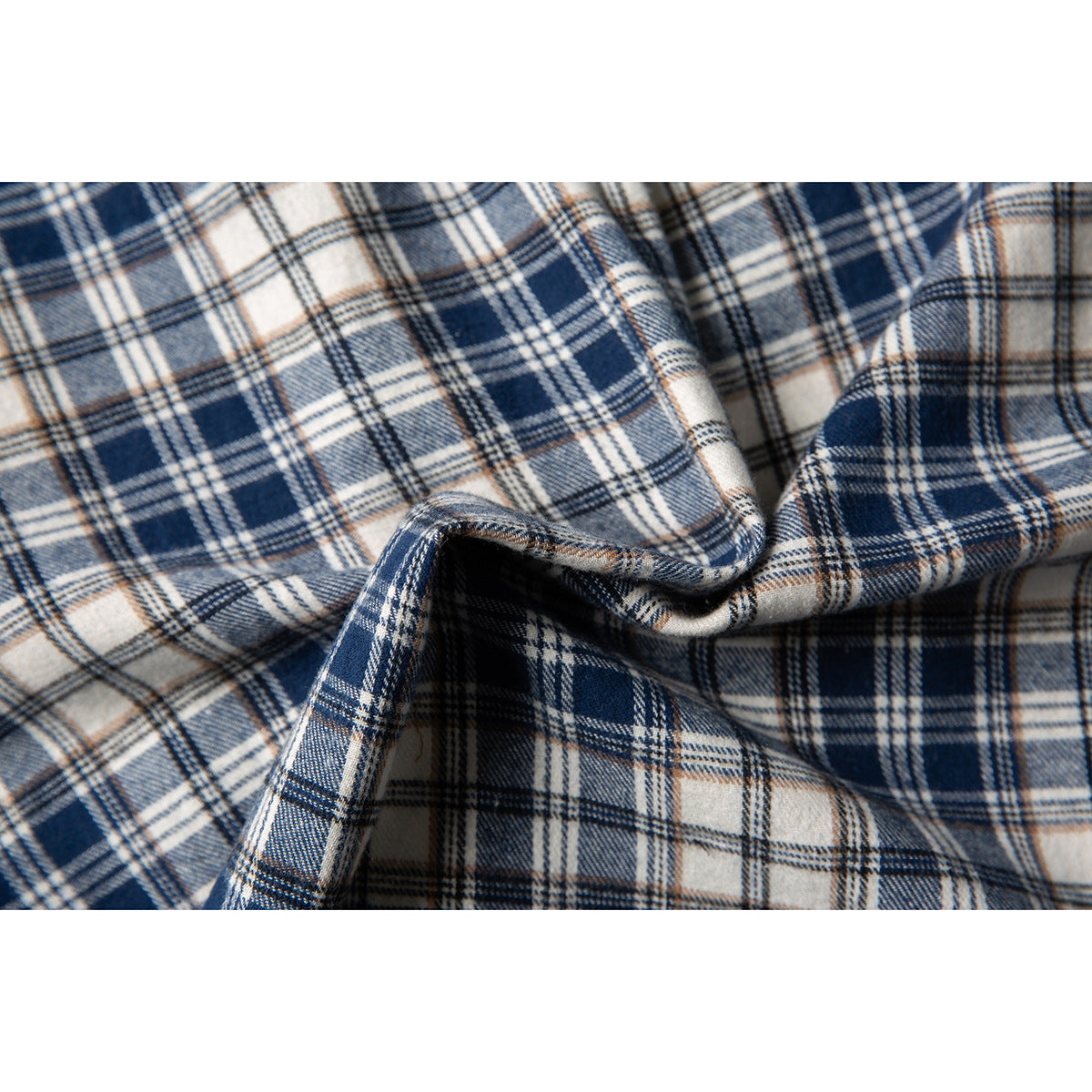 Macro view of navy, cream, and tan plaid shirt fabric, showing the woven-looking check pattern and folds.