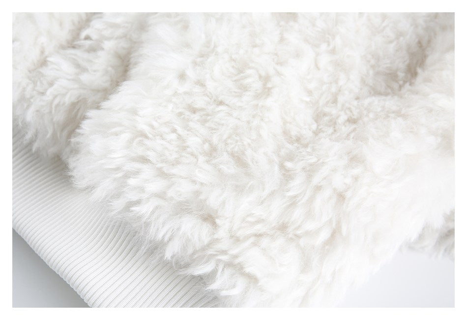 Close-up of white shaggy trim above a wide ribbed white hem.