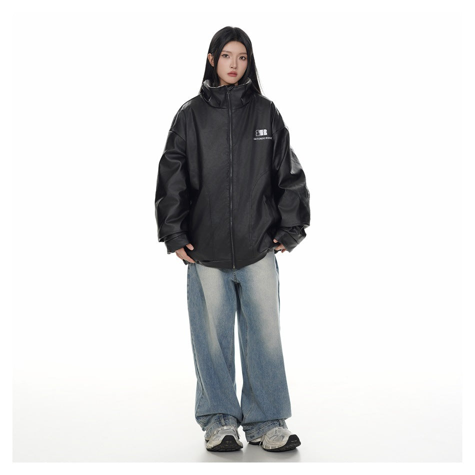 Model wearing a black oversized zip jacket with a high collar and small white chest logo, paired with loose light blue jeans.