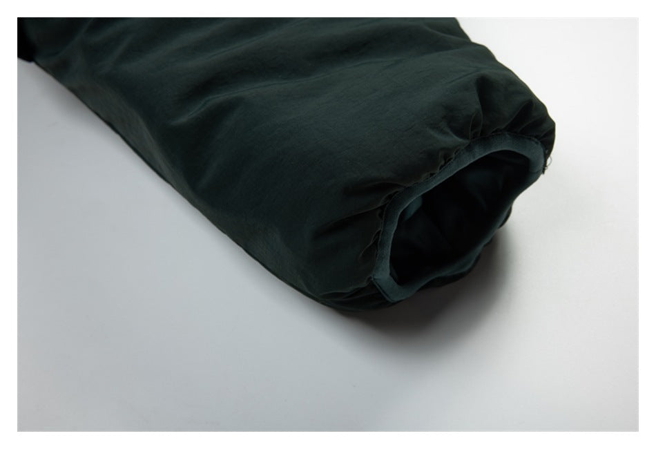 Close-up of a dark green garment hem opening with a stitched edge.