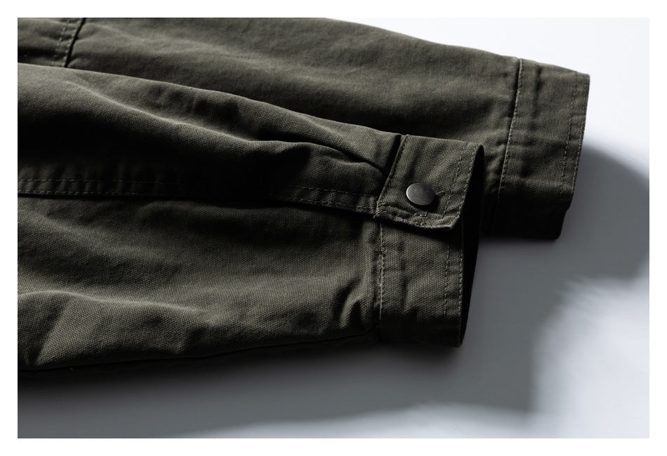 Close-up of a dark olive jacket sleeve cuff with a snap-button tab.