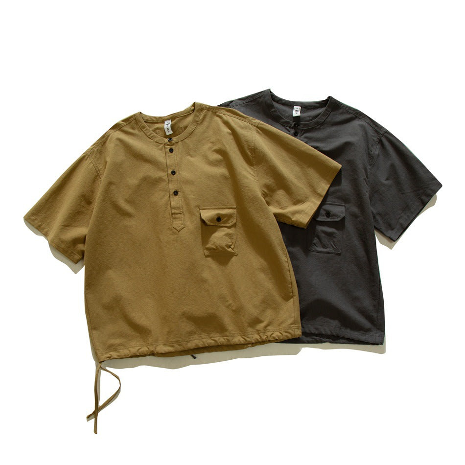 Tan and charcoal short-sleeve shirts with button plackets, chest pockets, and adjustable hem ties, shown from the front.