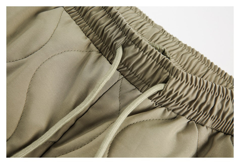 Close-up of the olive pants' gathered elastic waistband and drawstring openings.