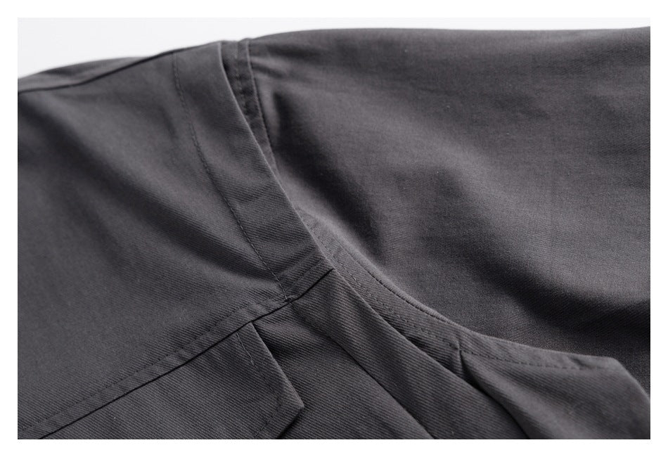 Close-up of dark charcoal shirt fabric and intersecting stitched seams.