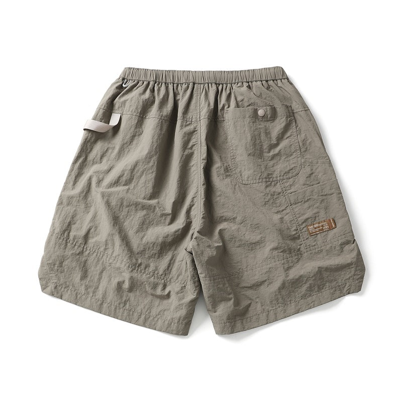 Taupe-gray shorts shown from the back, with an elastic waist, single patch pocket, side tab and small leg label.
