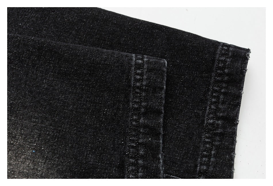 Close-up of a stitched hem on black pants.