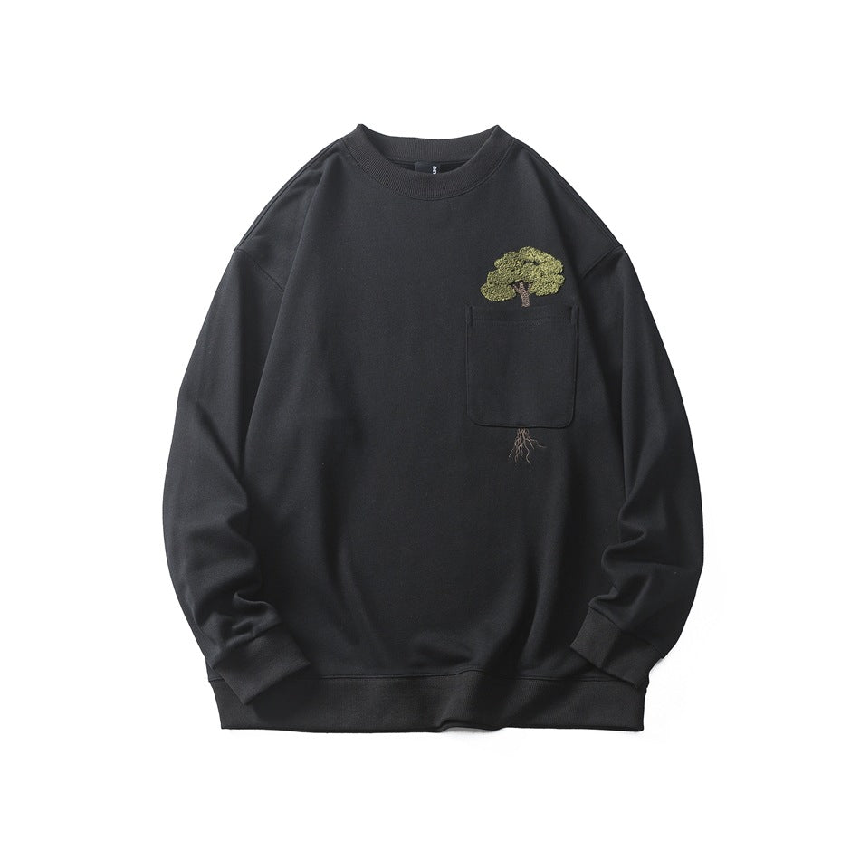Black crewneck sweatshirt flat lay with chest pocket and green embroidered tree with roots