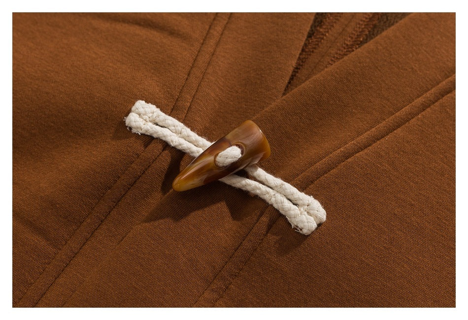 Close-up of a rust-brown coat's cream rope loop and brown toggle fastener.