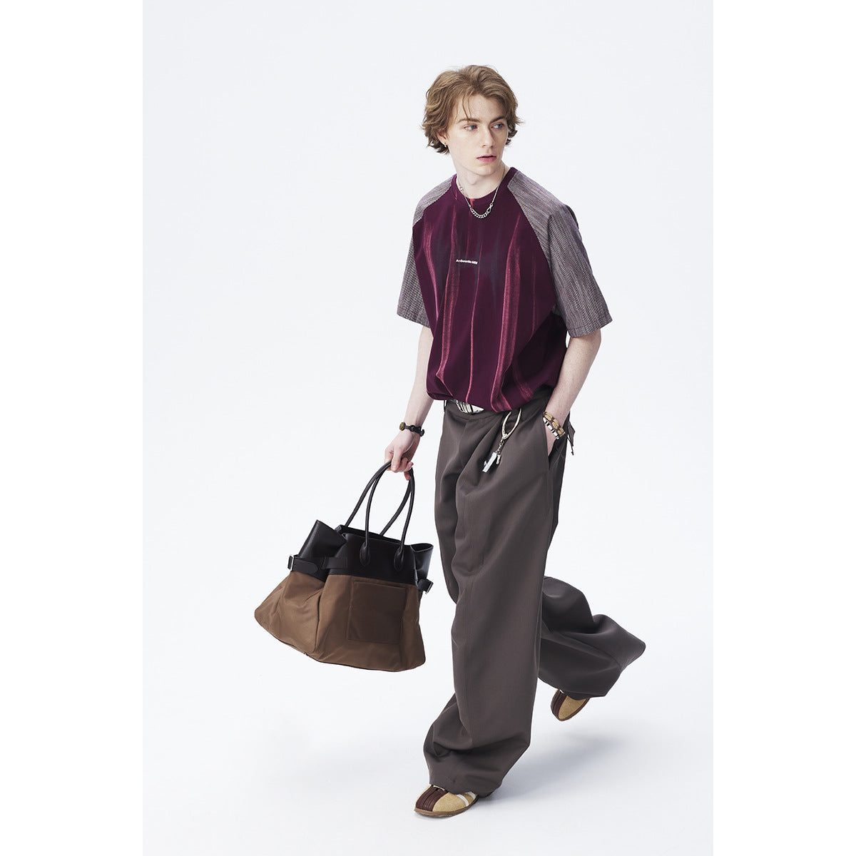 Model wearing a burgundy shirt with gray patterned sleeves and loose charcoal trousers.