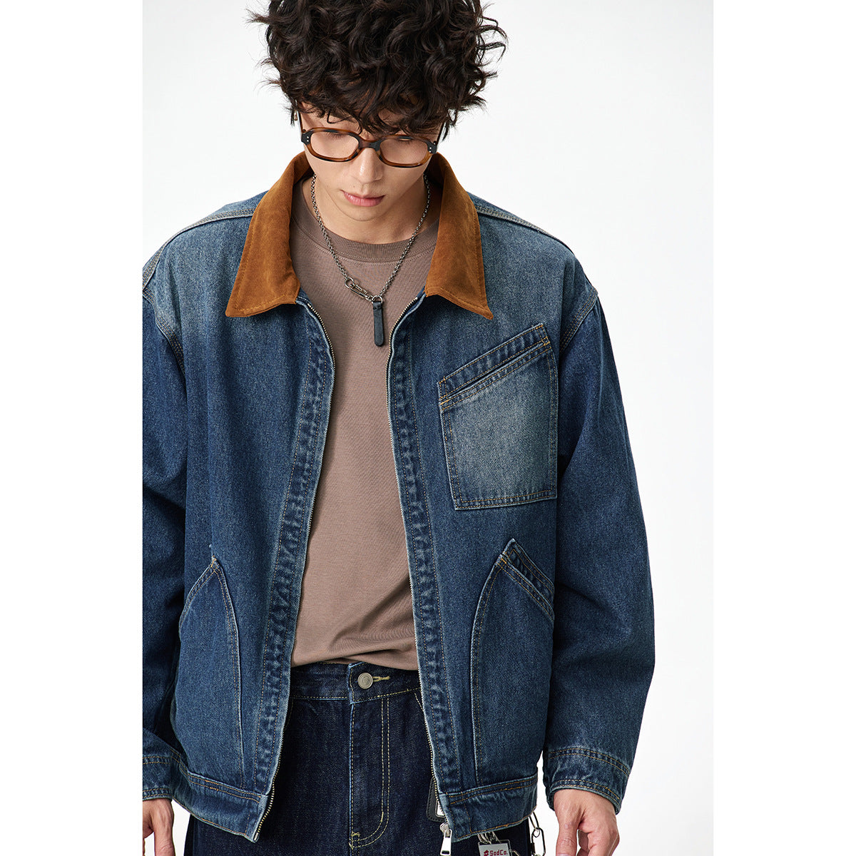 Model wearing a dark blue denim jacket with a brown collar, zip front and multiple stitched pockets.