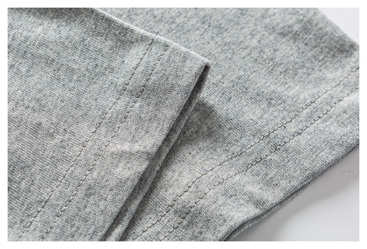 Close-up of folded edges and parallel stitching on heather gray shirt fabric.