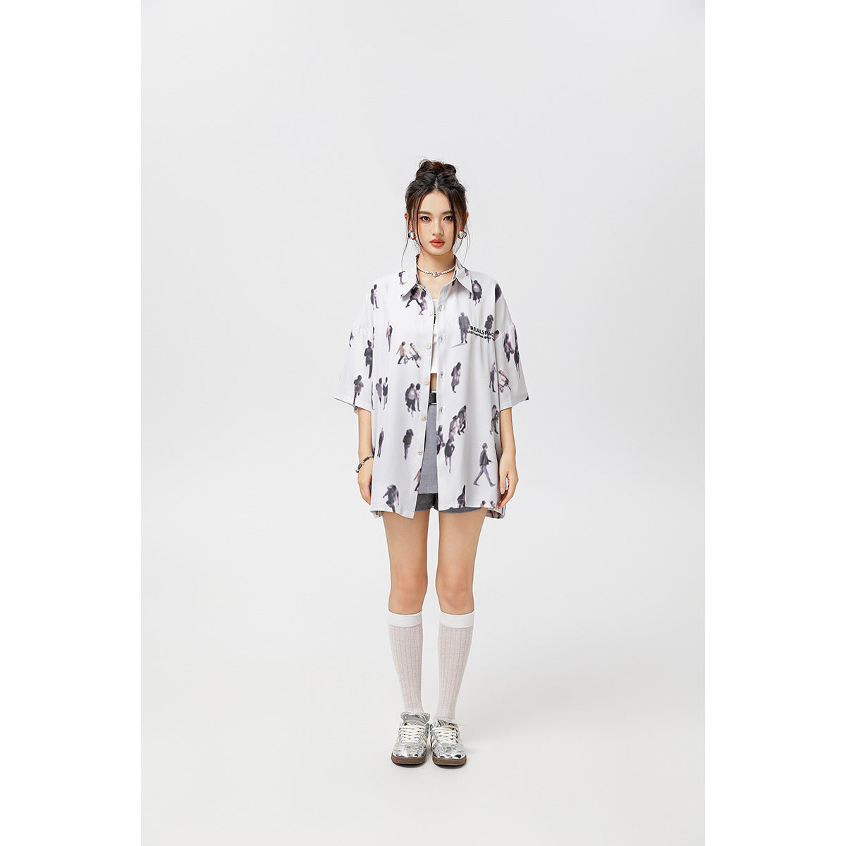 Model wearing a loose white short-sleeve button-up shirt with a dark all-over figure print.