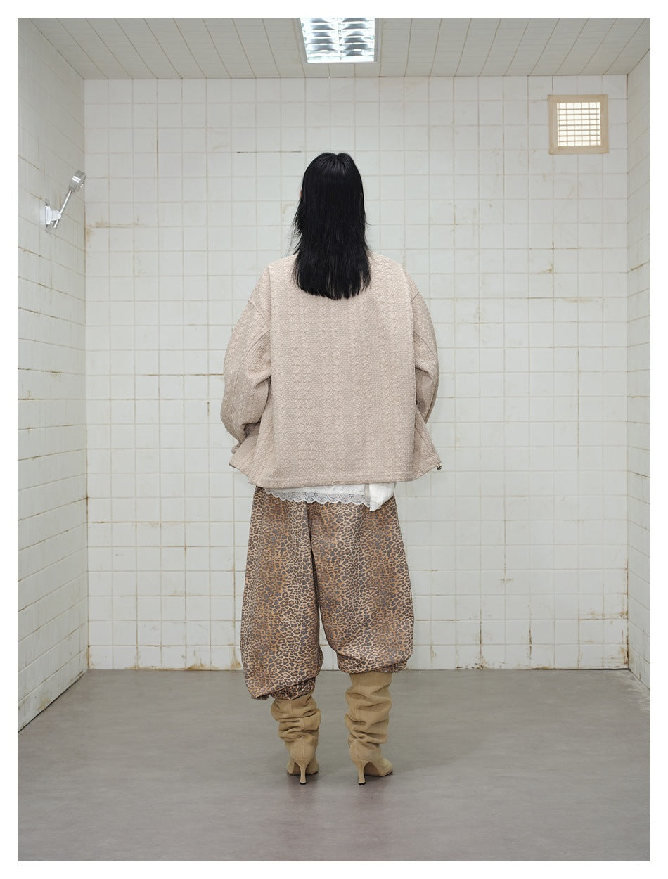 Back view of a person wearing a loose beige textured jacket with leopard-print pants and tan boots.