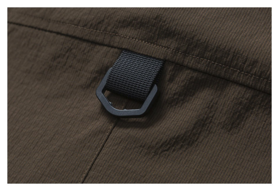 Close-up of a black loop and ring attached to dark brown garment fabric.