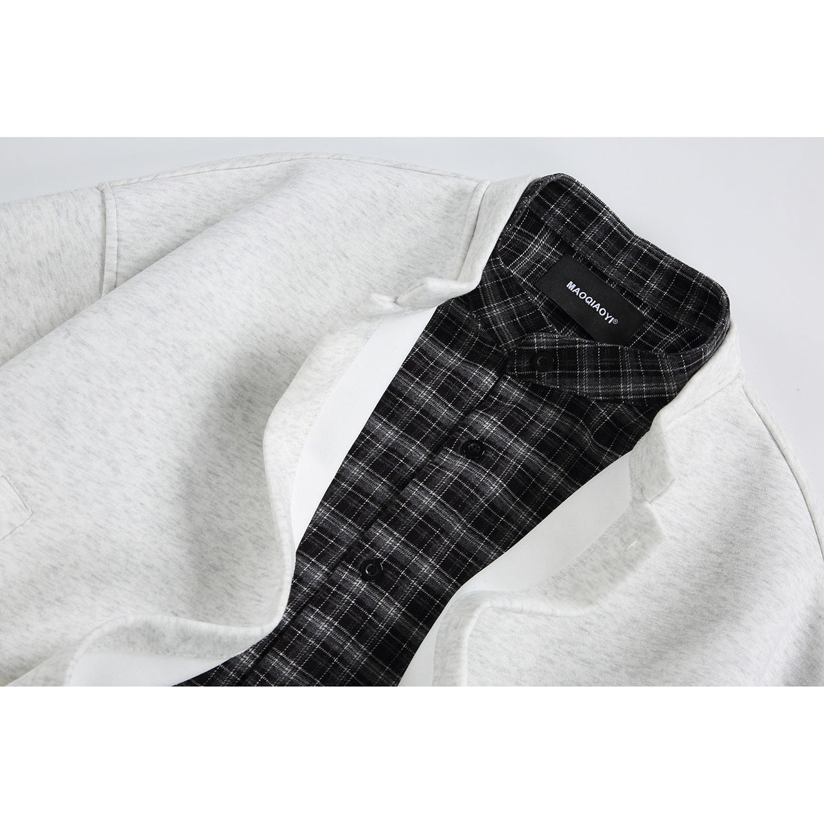 Close-up of a light gray jacket collar showing black-and-gray plaid lining, buttons, and a sewn neck label.