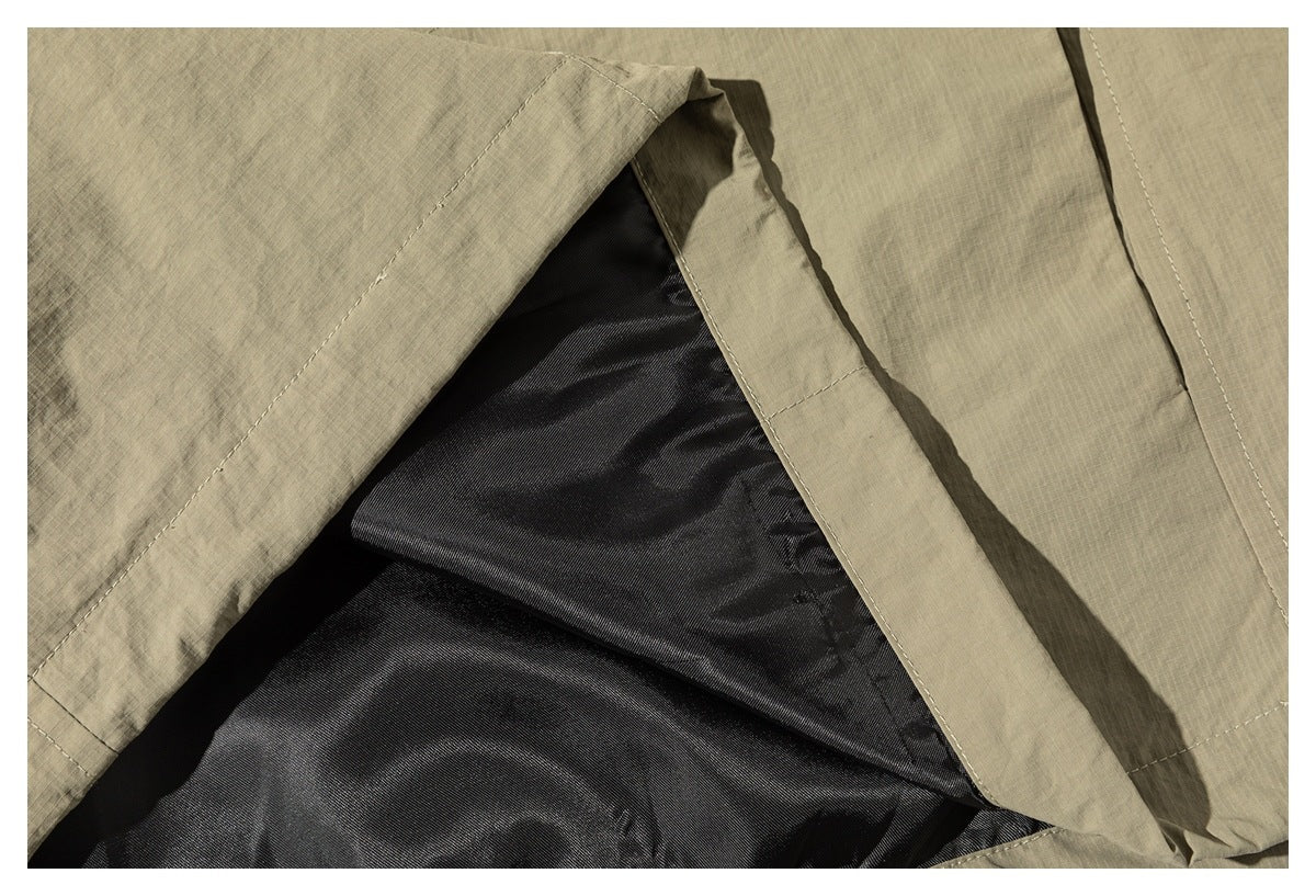 Close-up of the khaki jacket opened to show its dark inner lining and stitched seams.