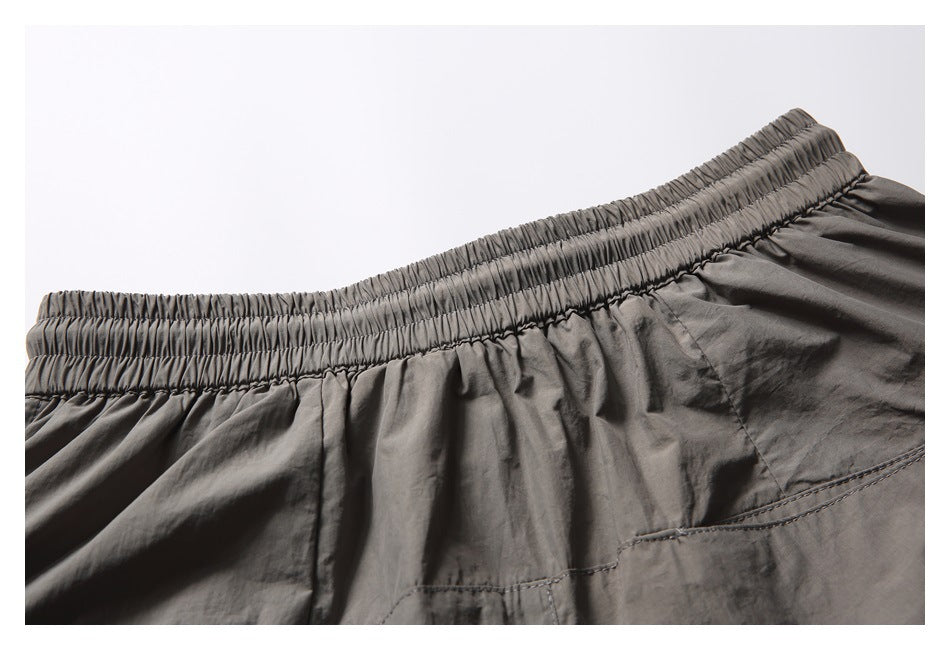 Close-up of the gathered elastic waistband and stitched pocket on charcoal-gray shorts.