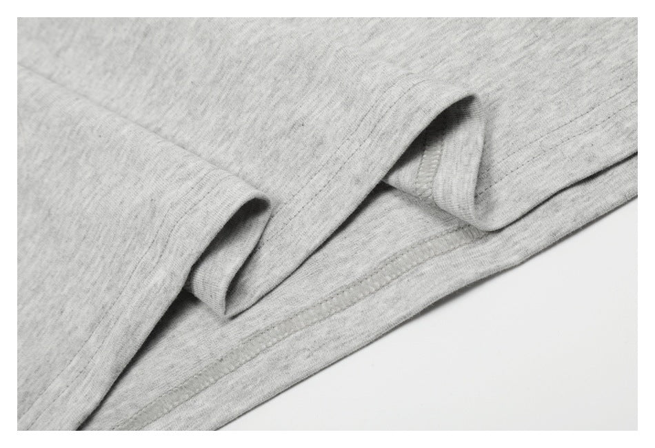 Close-up of folded light heather gray garment fabric showing a stitched edge and seam.
