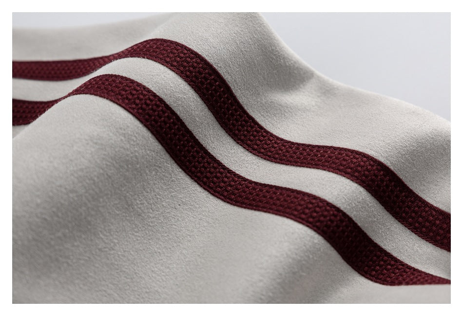 Close-up of light gray fabric with two curved burgundy textured trim bands.