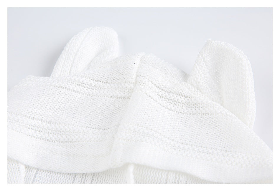 Close-up of white open-knit fabric with raised bands and folded garment edges.