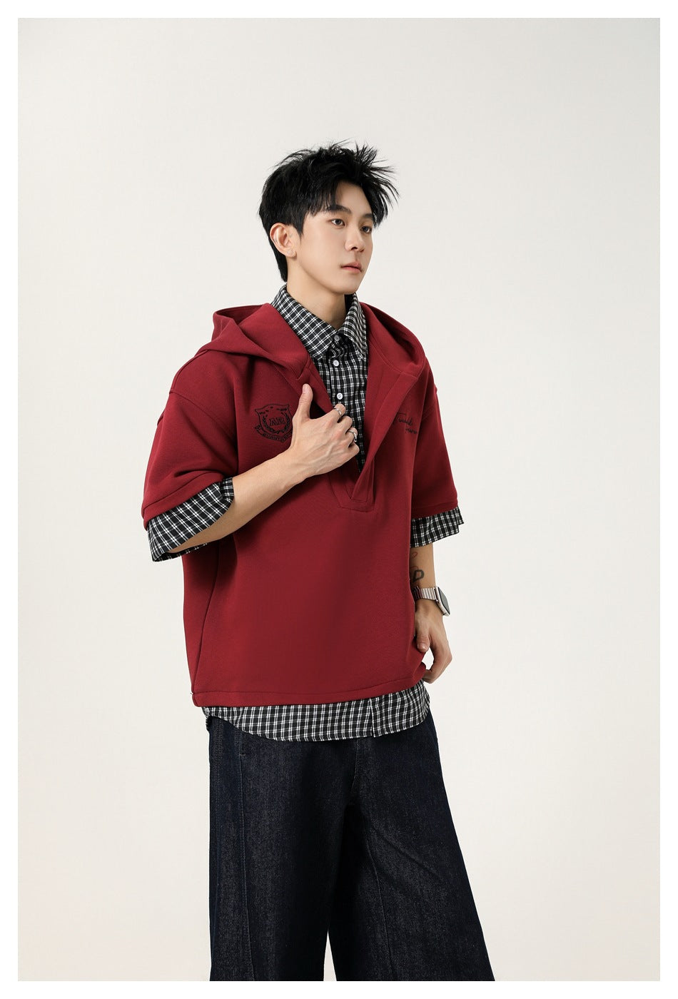 Three-quarter view of a model wearing a burgundy hooded pullover over a black-and-white checked shirt.