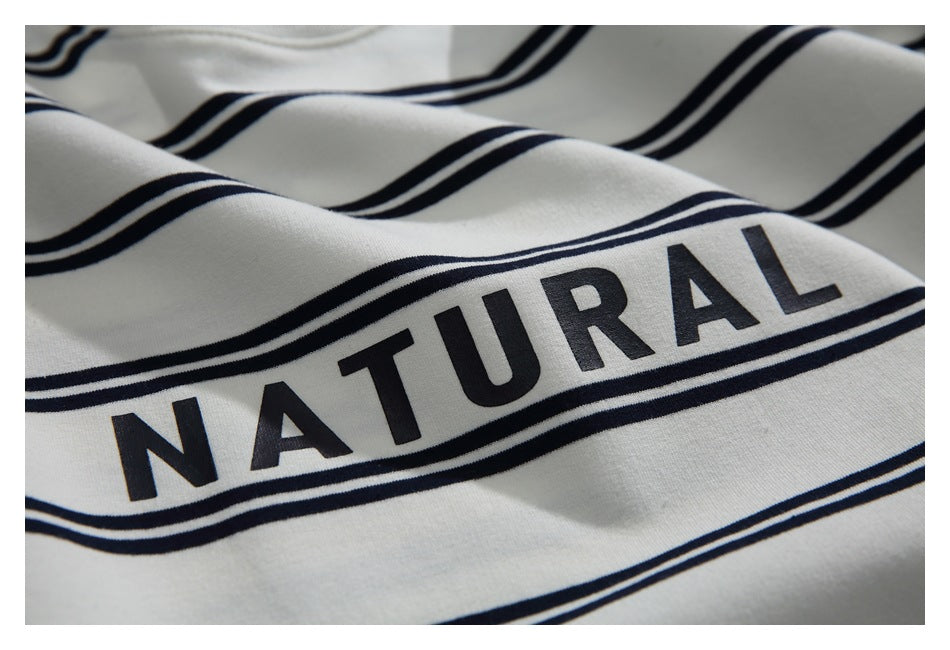Close-up of the “NATURAL” lettering printed between navy stripes on the ivory shirt.