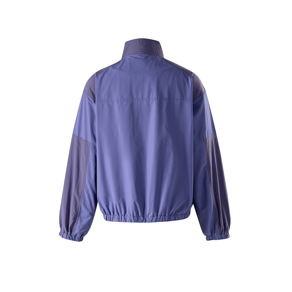 Back view of a blue-violet zip jacket with dark shoulder and sleeve panels and elastic cuffs and hem.