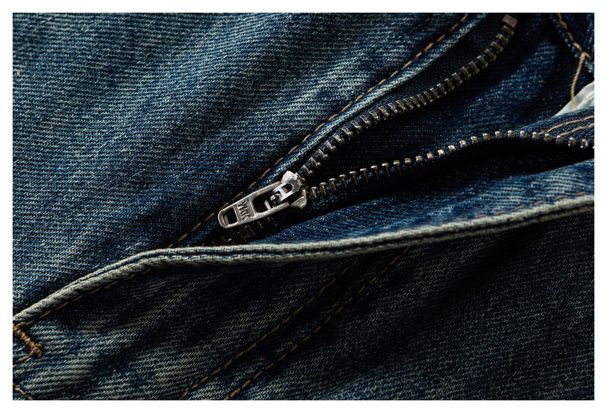 Close-up of dark blue jeans with an open metal zipper and visible denim stitching.