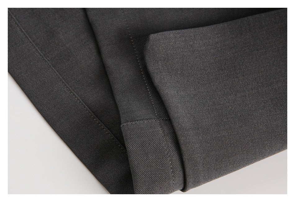 Close-up of the stitched hem on charcoal gray pants.