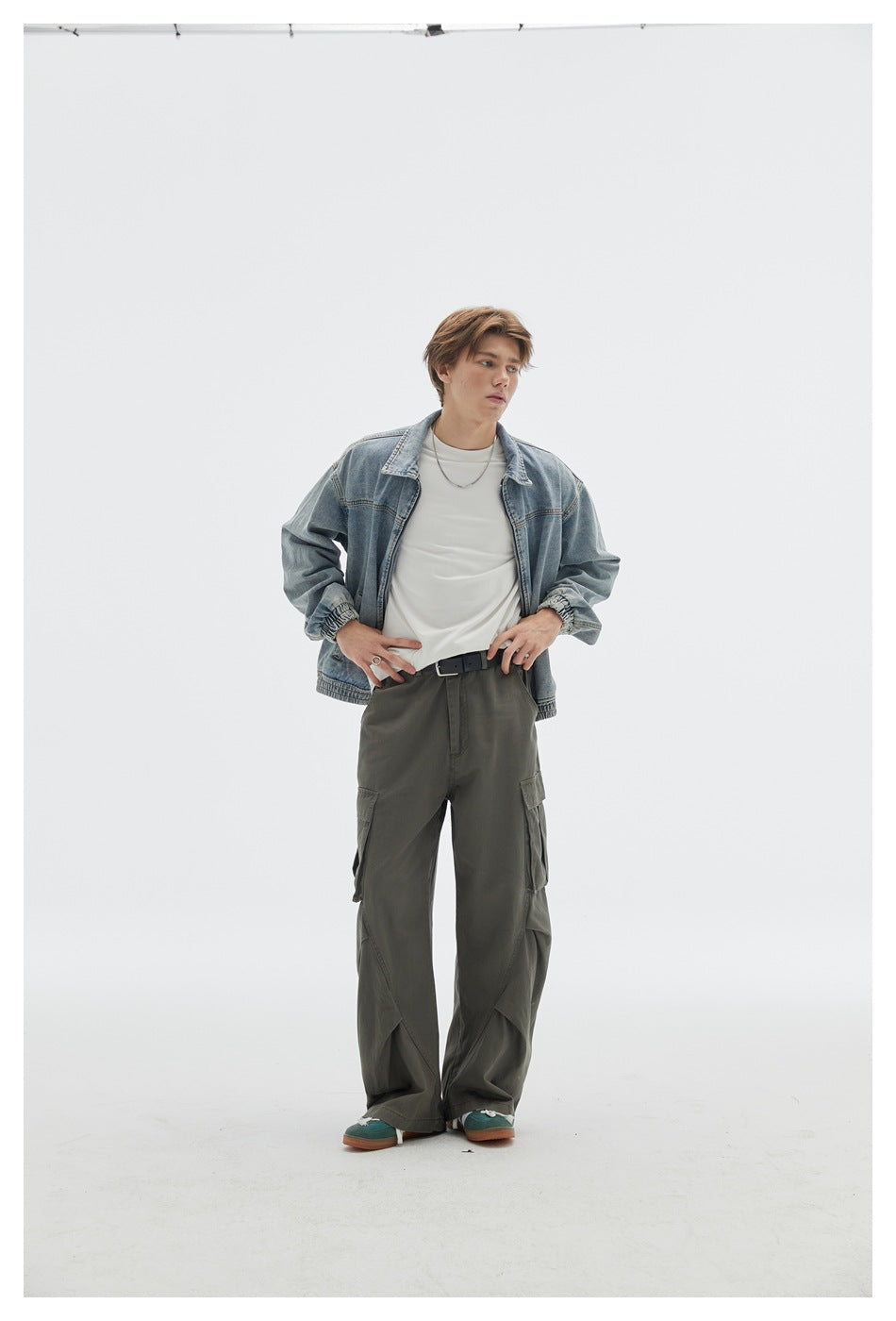 Model wearing a light blue denim jacket over a white shirt with loose olive cargo pants.