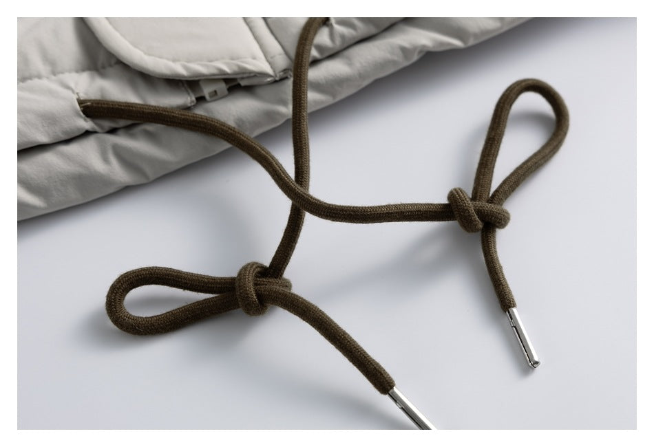 Close-up of brown drawcords with metal tips beside pale gray garment fabric.