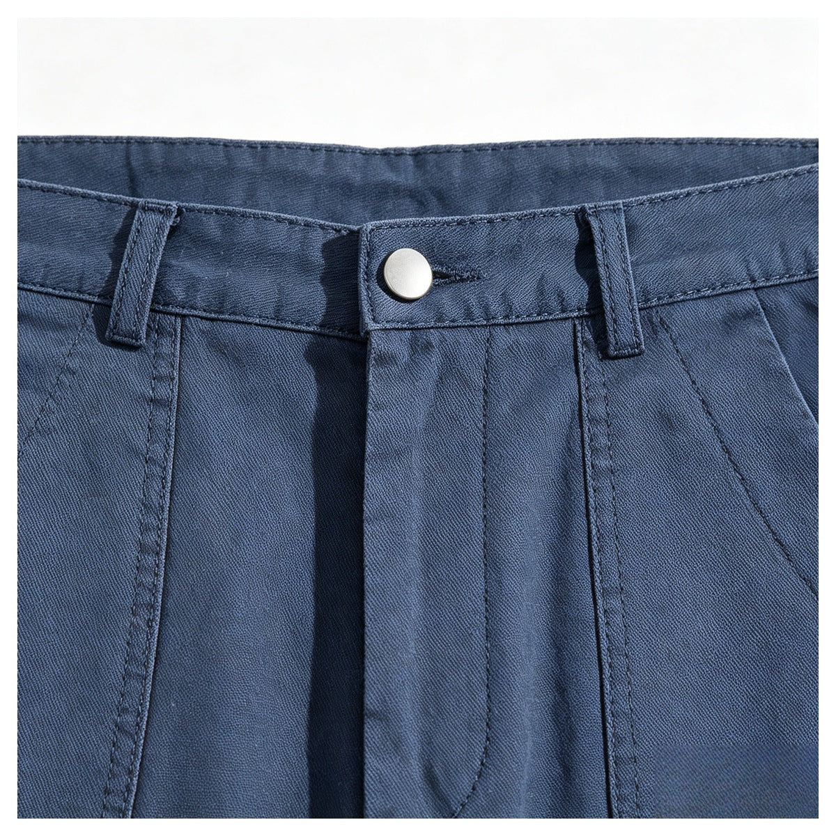 Close-up of blue trousers showing the front waistband, silver button, belt loops, and pleats.