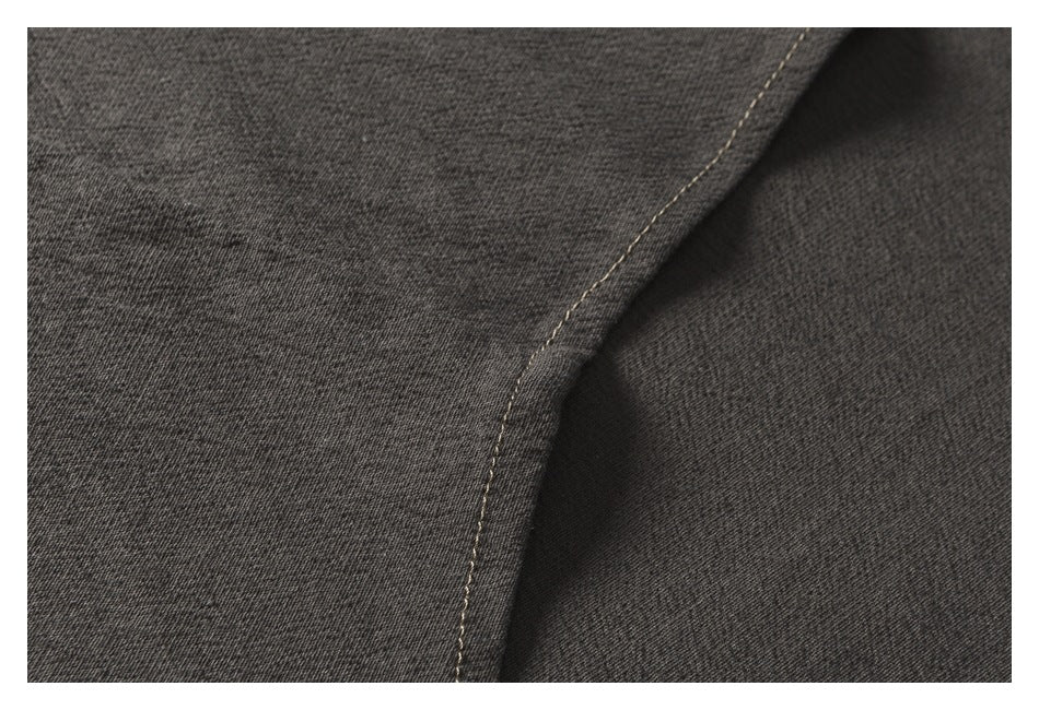 Close-up of dark charcoal garment fabric with a curved seam and light stitching.