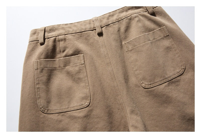 Cropped front view of tan trousers with belt loops and two patch pockets.