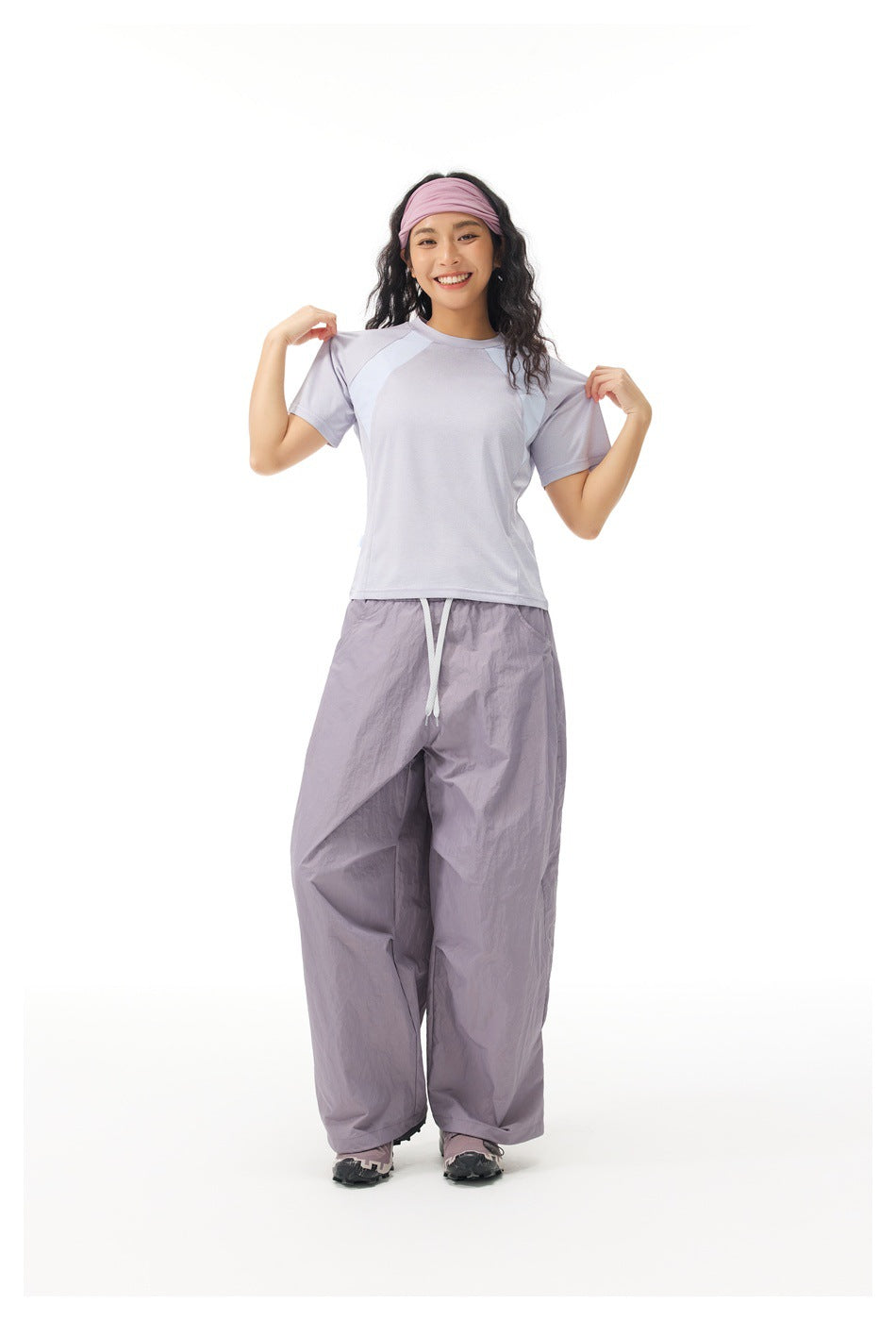 Model wearing a pale lavender color-block T-shirt and loose lavender-gray drawstring pants, facing forward.