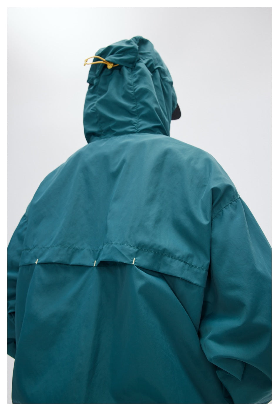 Close-up of the teal jacket's back hood and stitched rear vent detail.