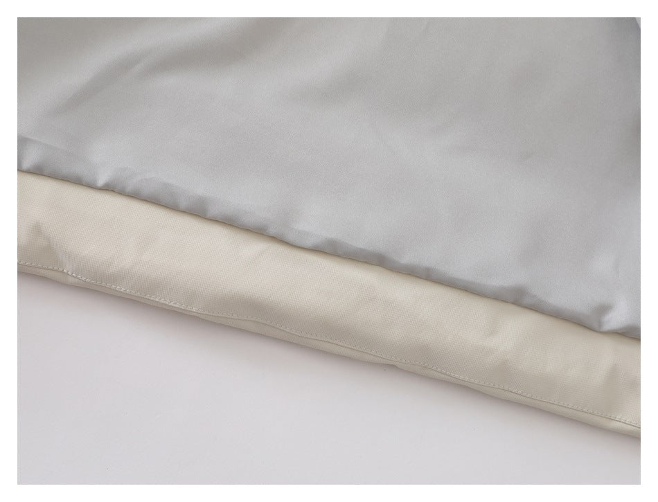 Close-up of the cream jacket's lower edge with a pale gray panel above it.