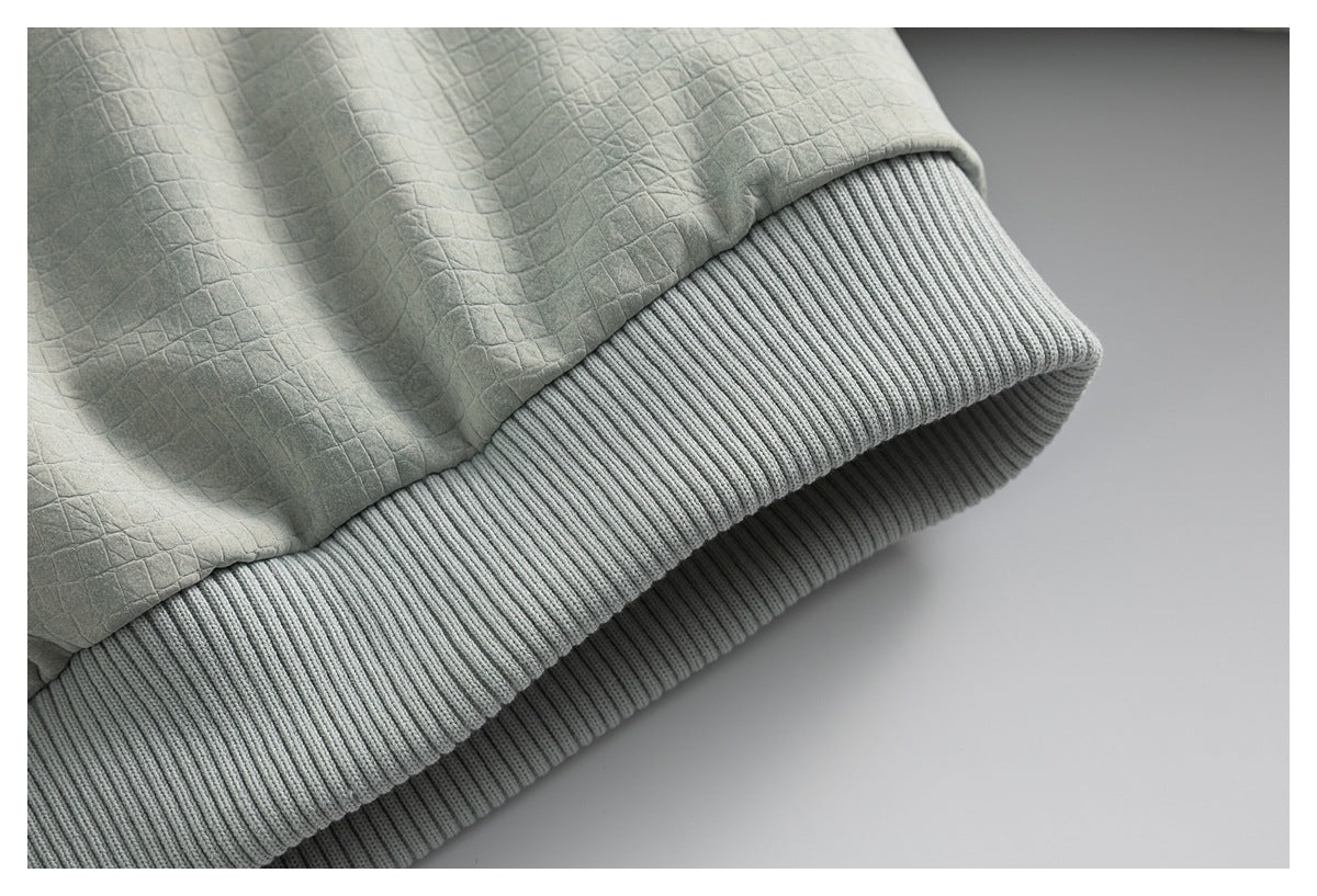 Close-up of the jacket's pale sage-gray grid-textured fabric and wide ribbed hem.