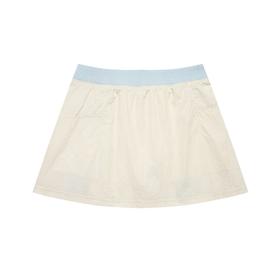 Flat lay of a cream flared skirt with a wide pale blue ribbed waistband and subtle side pockets.