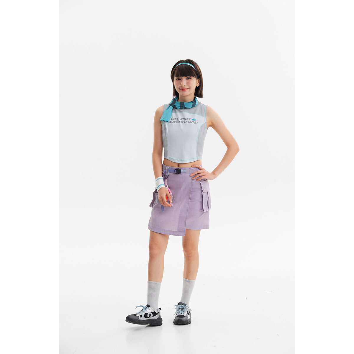 Model wearing a white sleeveless crop top, blue scarf and lavender cargo mini skirt.