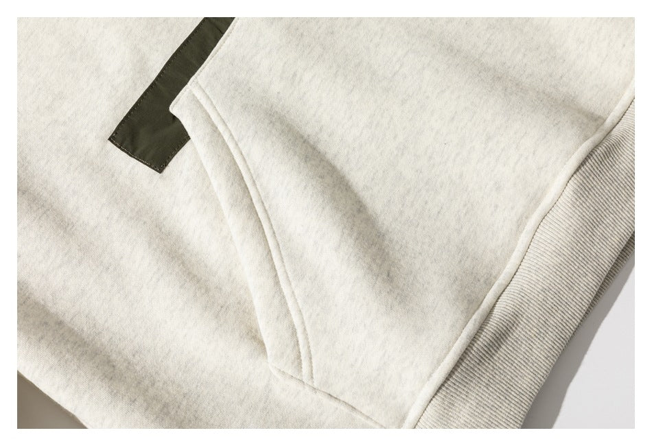 Close-up of the off-white hoodie’s front pouch pocket, ribbed hem, and olive fabric accent.