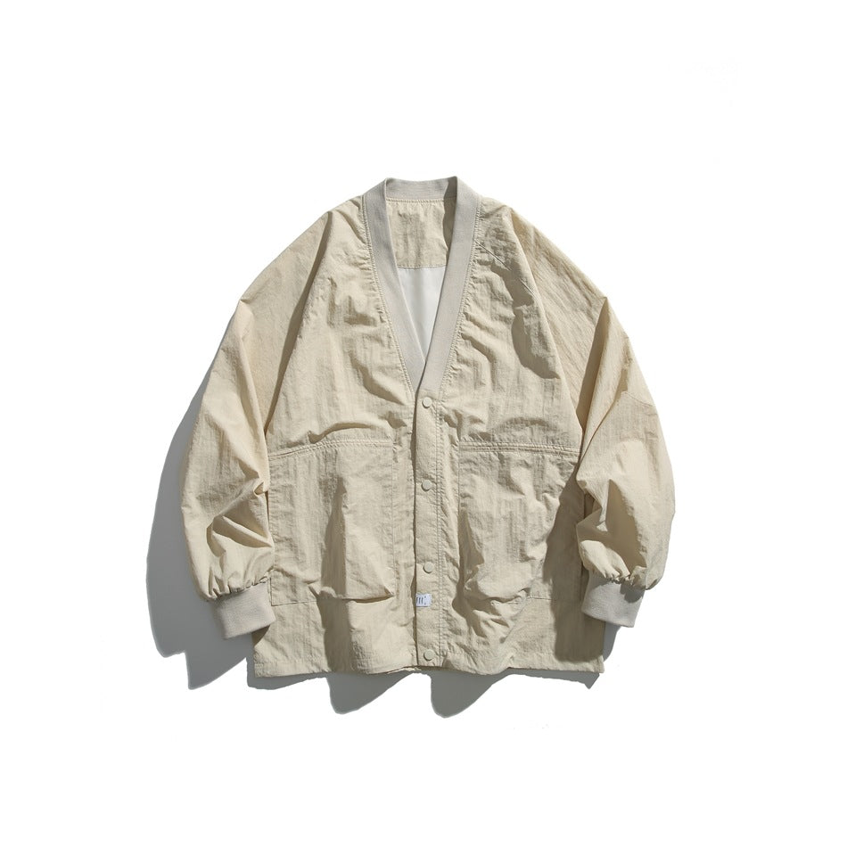 Beige V-neck snap-front jacket with ribbed collar trim, large front pockets and ribbed cuffs, laid flat