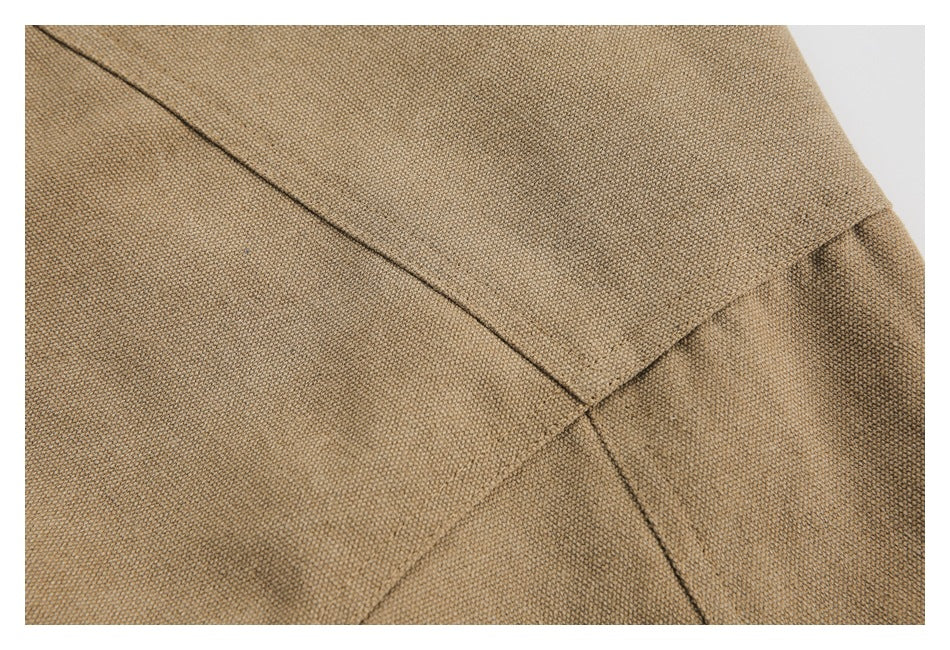Close-up of intersecting seams on tan woven garment fabric.