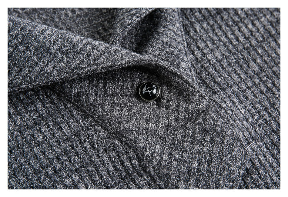 Close-up of a dark button on the charcoal gray knit garment beneath a folded collar edge.