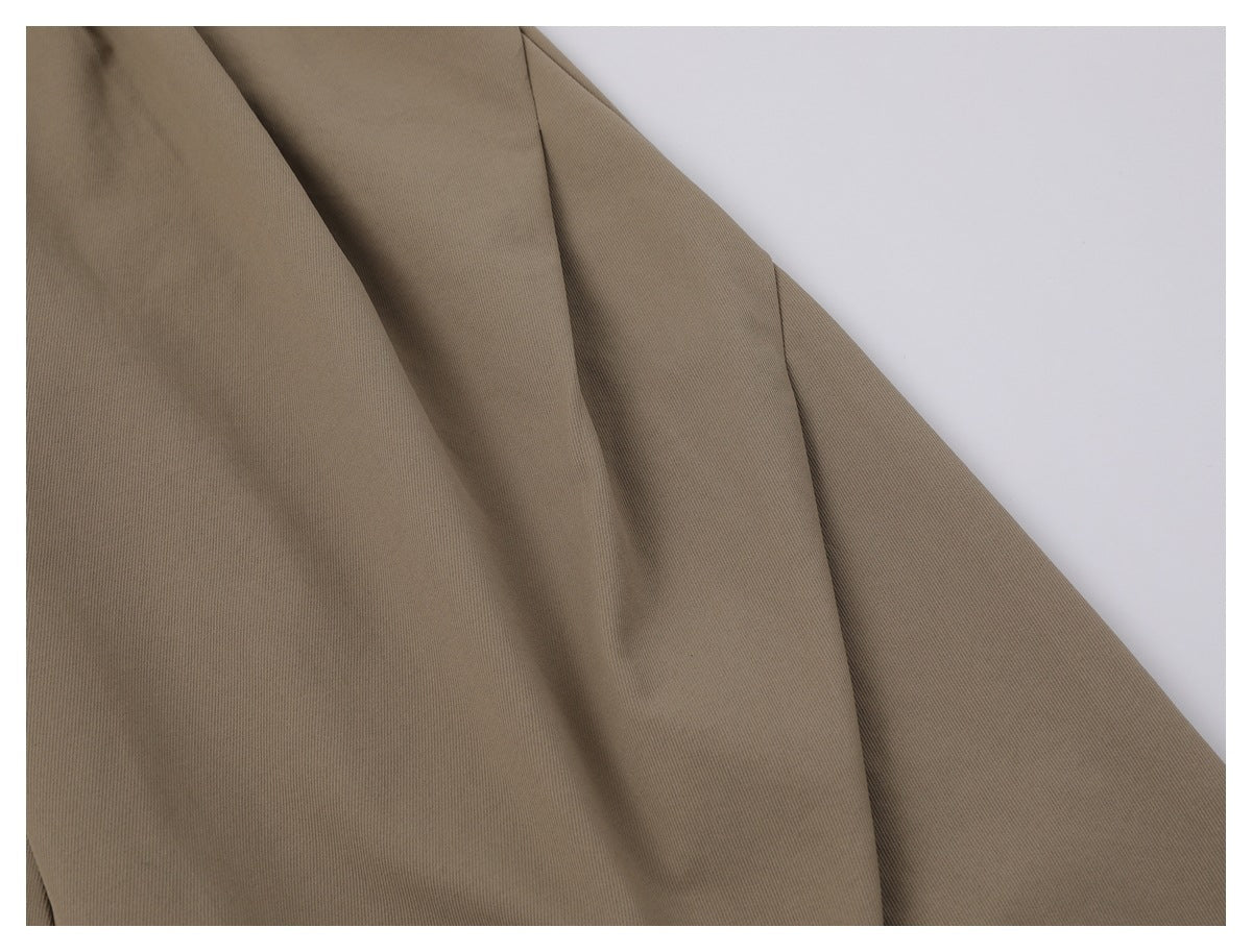 Close-up of taupe trouser fabric draped to show its seams and texture.
